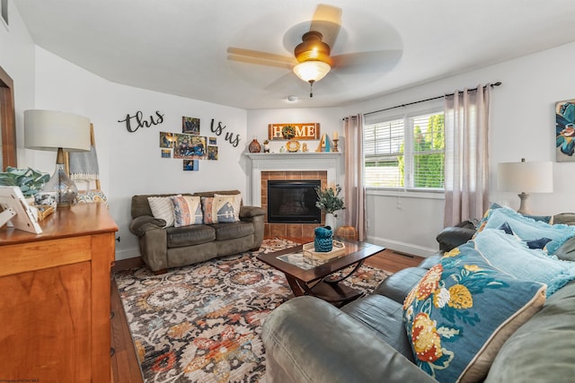 living room featuring ceiling fan, hardwood / wood-style flooring, and a fireplace