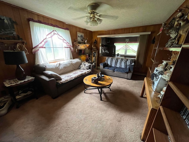 living room with wood walls, ceiling fan, carpet floors, and a textured ceiling