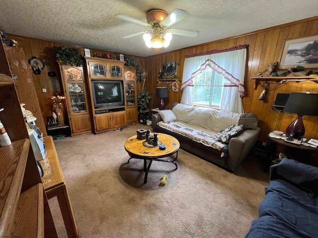 living room featuring a textured ceiling, wood walls, light carpet, and ceiling fan
