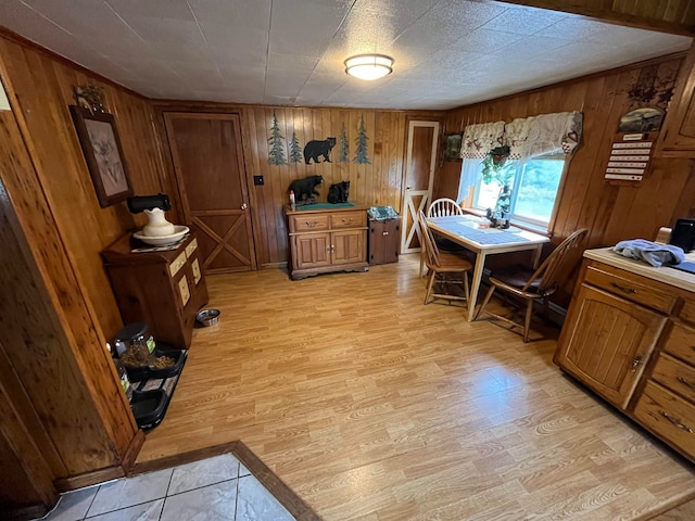 dining space with light wood-type flooring and wood walls