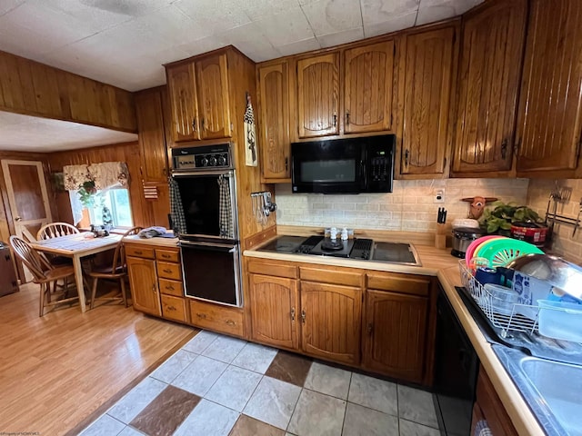 kitchen featuring black appliances, light hardwood / wood-style flooring, and tasteful backsplash