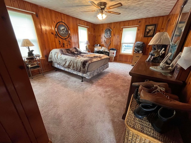 bedroom featuring a textured ceiling, carpet flooring, wood walls, and ceiling fan