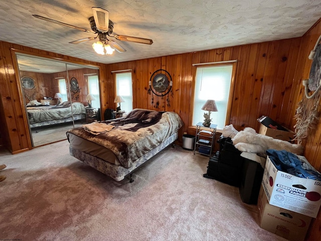 bedroom with a closet, wood walls, multiple windows, and ceiling fan