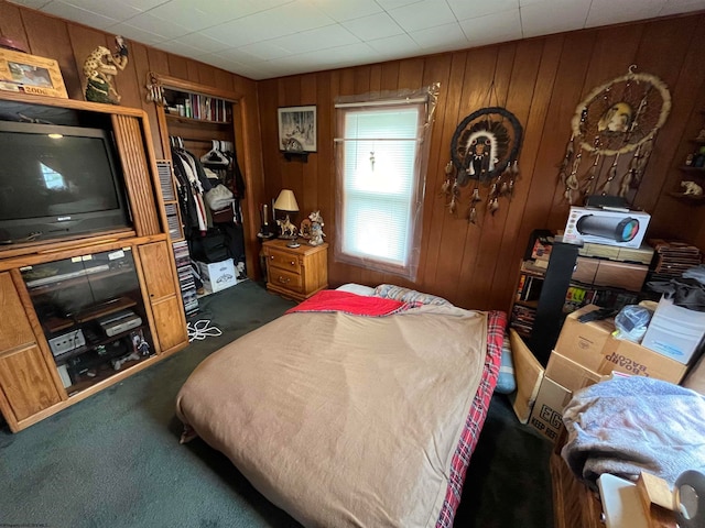 bedroom with wood walls, dark carpet, and a closet