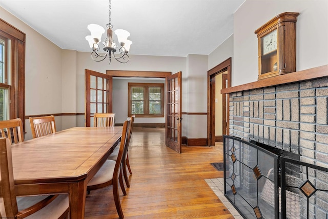 dining space with an inviting chandelier, light wood-type flooring, and french doors