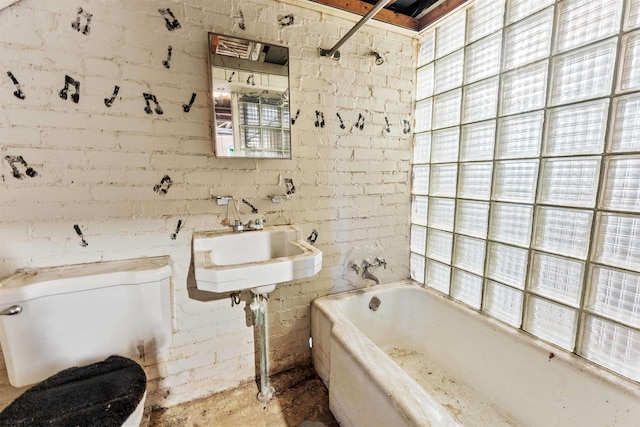 full bathroom with brick wall, sink, washtub / shower combination, and toilet