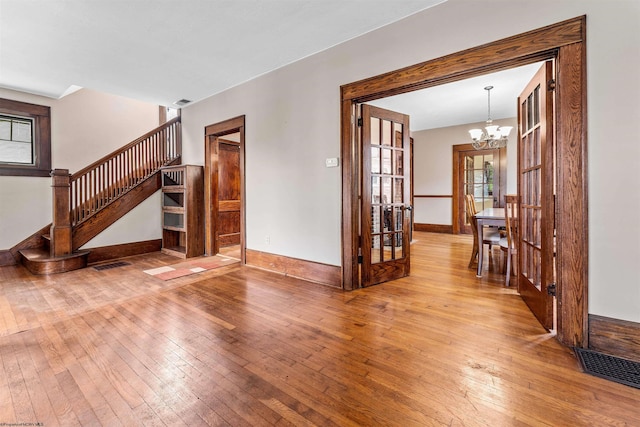 unfurnished living room featuring a notable chandelier, a wealth of natural light, and hardwood / wood-style flooring