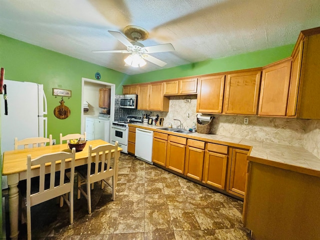 kitchen featuring washer and dryer, white appliances, backsplash, tile countertops, and ceiling fan