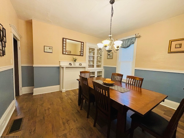 dining area with dark hardwood / wood-style floors and a notable chandelier