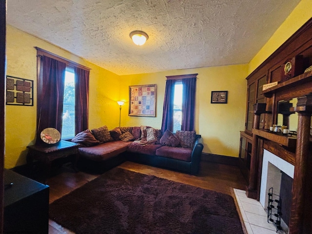 living room with light hardwood / wood-style flooring, a wealth of natural light, a tiled fireplace, and a textured ceiling