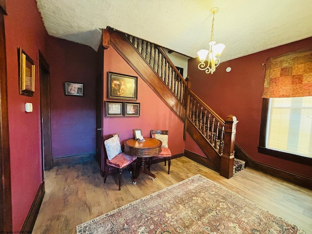 interior space featuring wood-type flooring, a notable chandelier, and a textured ceiling