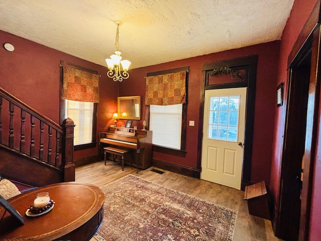 entryway with a notable chandelier, light hardwood / wood-style floors, and a textured ceiling