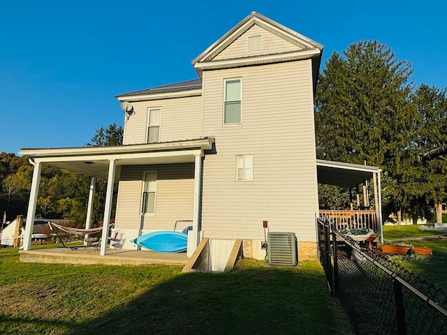 rear view of property with a lawn and central AC unit