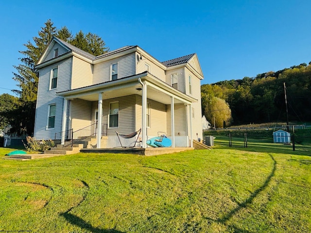 back of house featuring a yard, a storage unit, and a porch