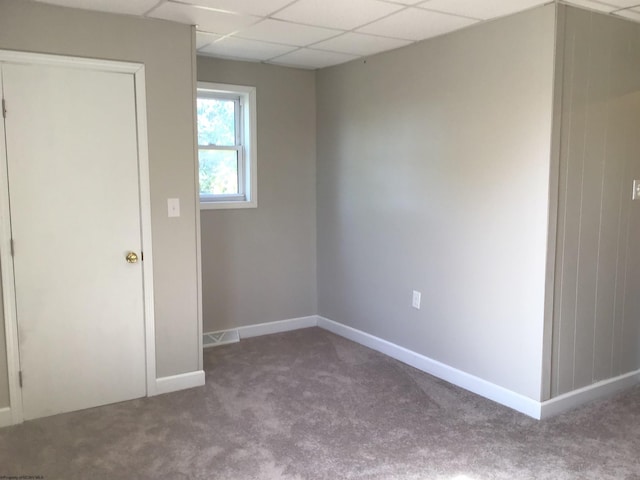 carpeted spare room with a drop ceiling