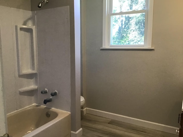 bathroom with hardwood / wood-style flooring, toilet, and shower / washtub combination