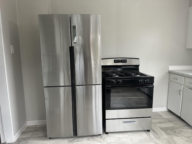 kitchen with white cabinetry, stainless steel fridge, and range with gas stovetop