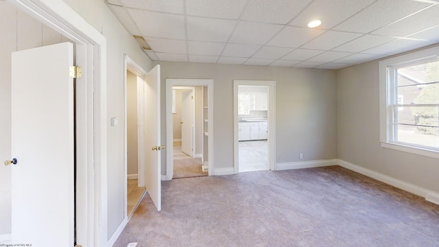 unfurnished bedroom featuring light carpet and a drop ceiling