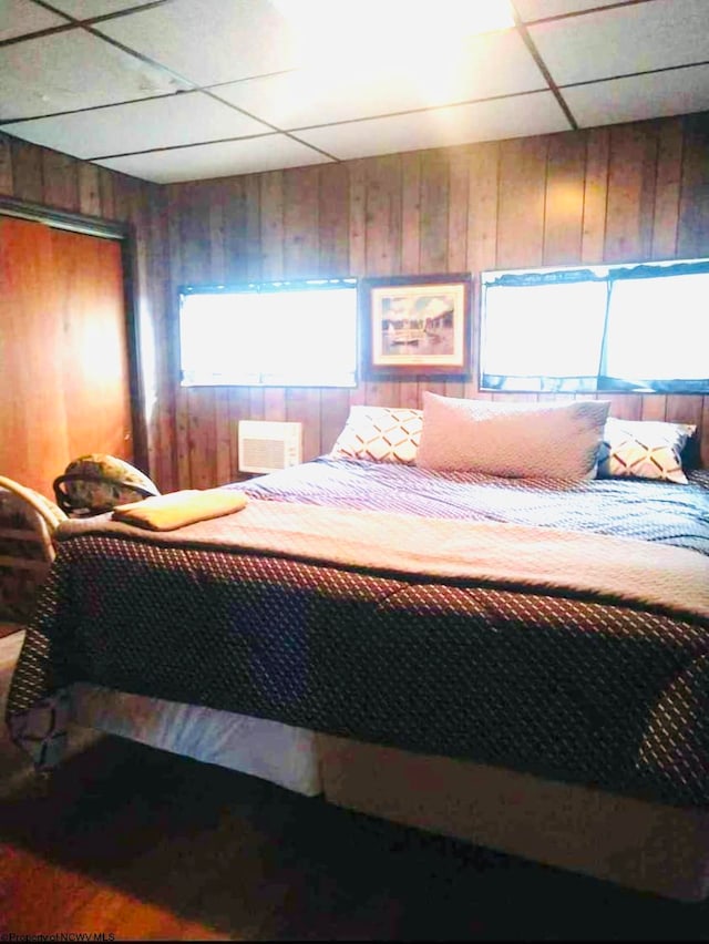 bedroom featuring wood walls, a closet, and a paneled ceiling