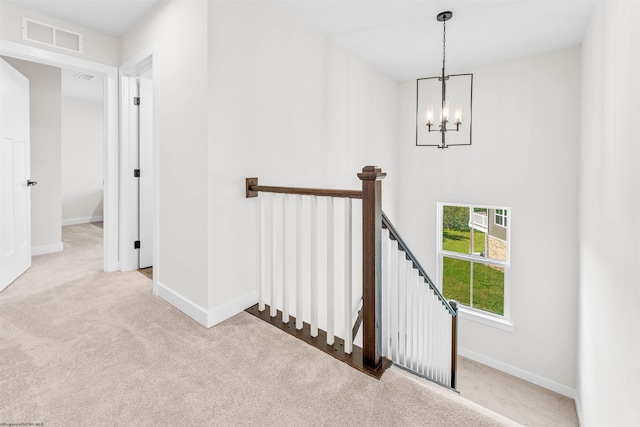 staircase with carpet flooring and a notable chandelier