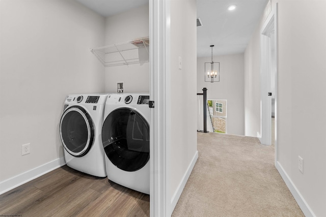 laundry room featuring washer and clothes dryer, light hardwood / wood-style floors, and an inviting chandelier