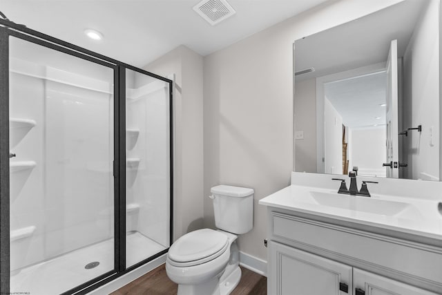 bathroom with hardwood / wood-style floors, vanity, toilet, and a shower with door