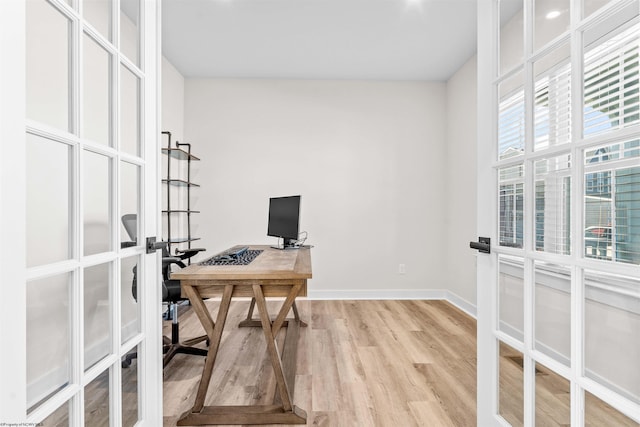 office with light hardwood / wood-style flooring and french doors