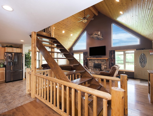 stairway with wooden ceiling, a stone fireplace, high vaulted ceiling, and hardwood / wood-style flooring