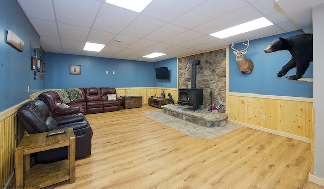 living room featuring a paneled ceiling, hardwood / wood-style floors, and a wood stove