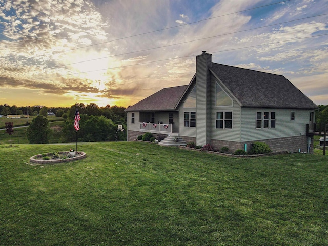 back house at dusk featuring a lawn