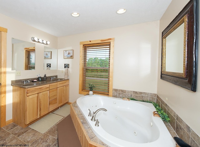 bathroom with tiled tub and vanity