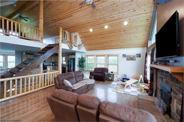 living room with wood-type flooring, a stone fireplace, wood ceiling, and high vaulted ceiling