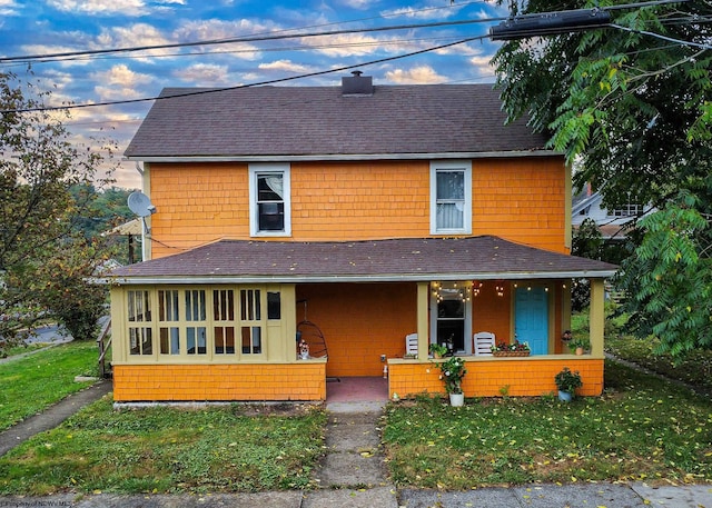 farmhouse with covered porch and a lawn