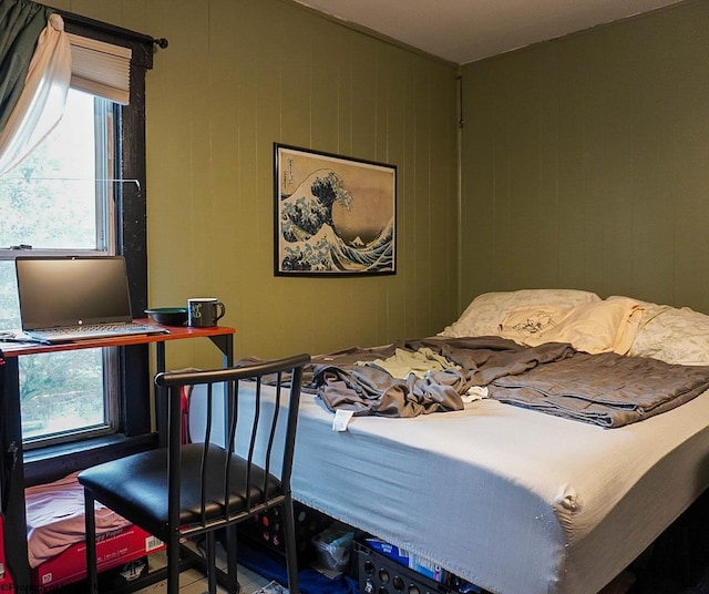 bedroom featuring wooden walls and multiple windows