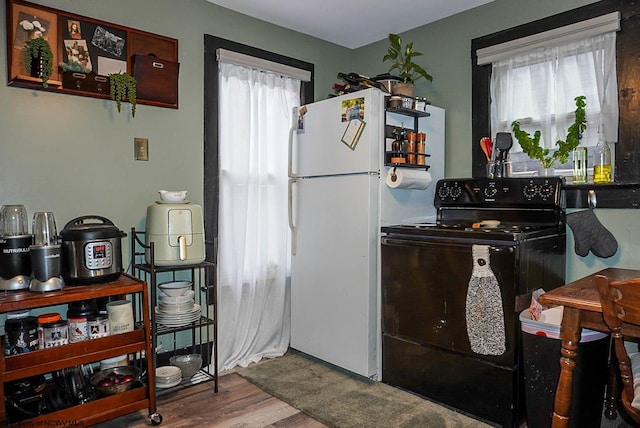 kitchen featuring white refrigerator, hardwood / wood-style floors, and black range with electric stovetop