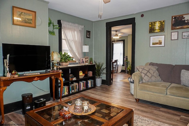 living room featuring wood-type flooring, crown molding, and ceiling fan