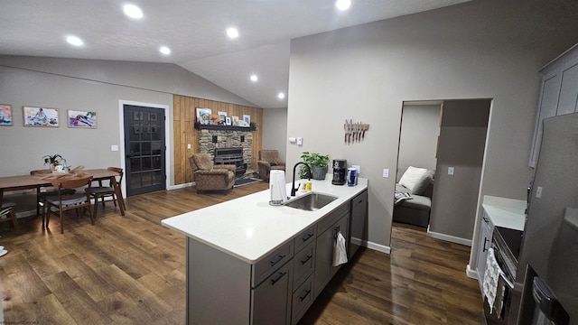 kitchen with a stone fireplace, gray cabinetry, sink, kitchen peninsula, and vaulted ceiling