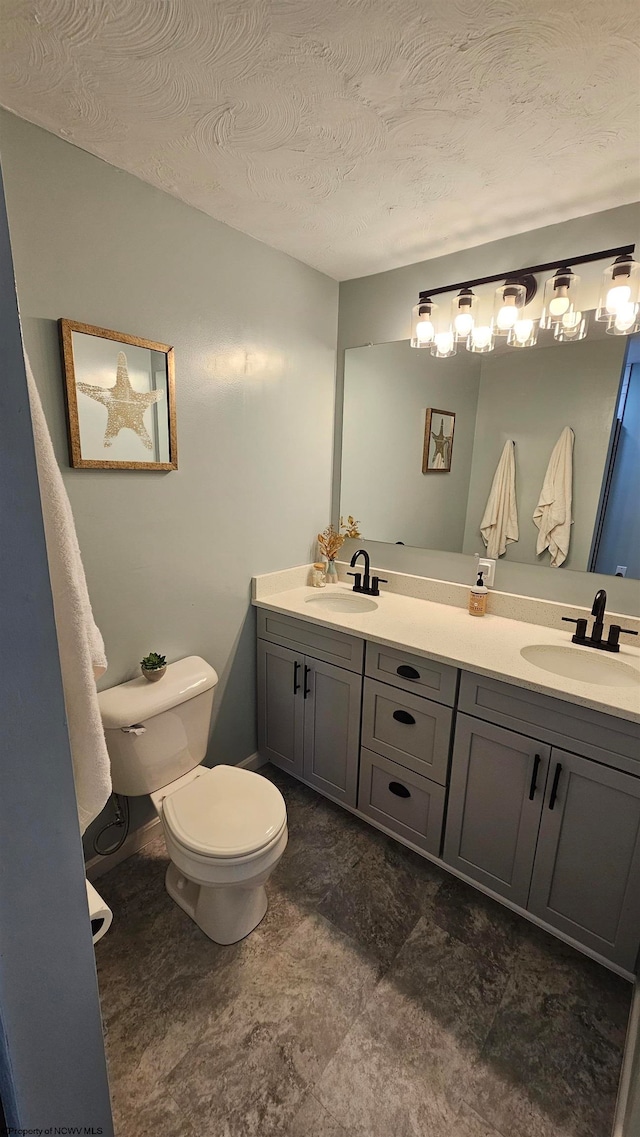 bathroom featuring a textured ceiling, vanity, and toilet