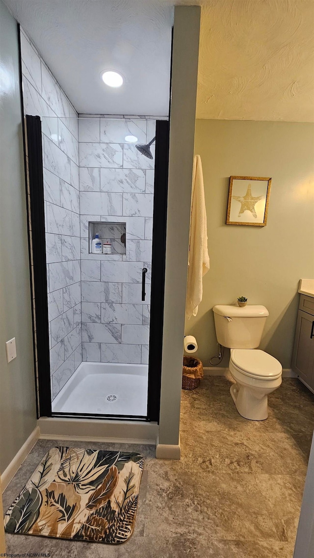 bathroom with toilet, tiled shower, and vanity