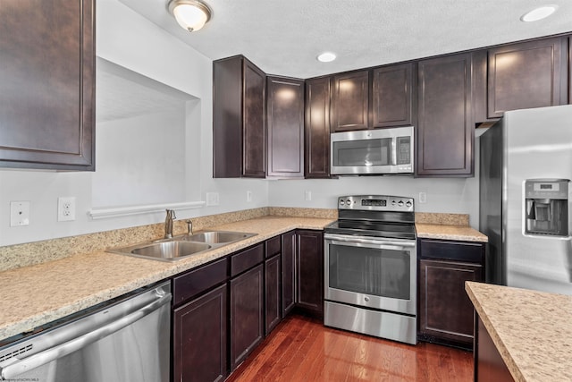 kitchen with a textured ceiling, stainless steel appliances, dark wood-type flooring, and sink