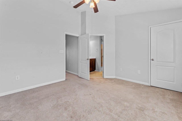 interior space featuring ensuite bathroom, high vaulted ceiling, ceiling fan, and light colored carpet