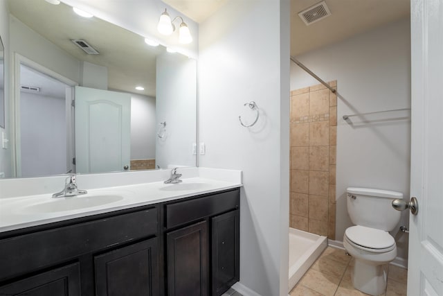 bathroom featuring a tile shower, vanity, tile patterned flooring, and toilet