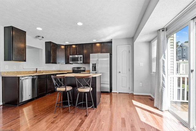 kitchen featuring a center island, stainless steel appliances, sink, light hardwood / wood-style floors, and a kitchen bar