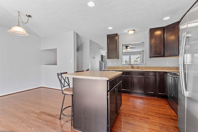 kitchen with a center island, hardwood / wood-style flooring, hanging light fixtures, a breakfast bar area, and appliances with stainless steel finishes