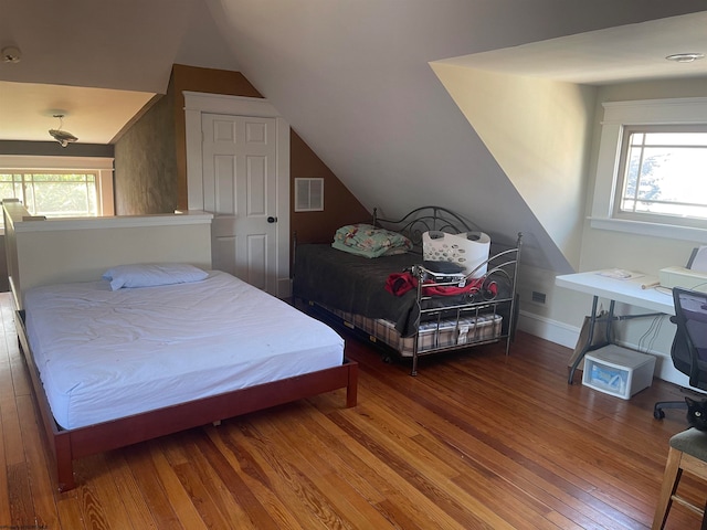 bedroom featuring vaulted ceiling, multiple windows, and wood-type flooring