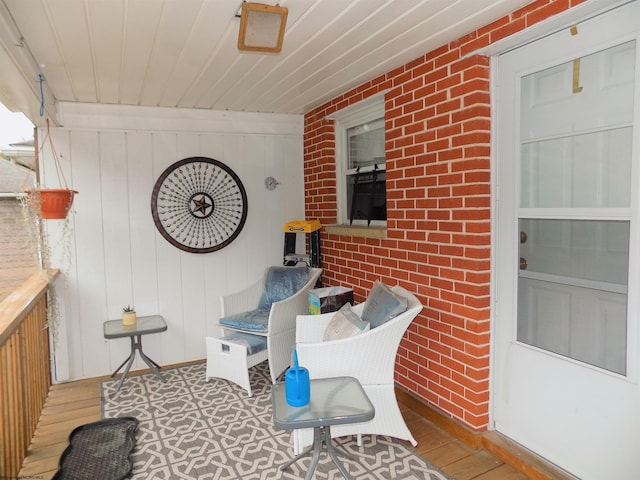 interior space with hardwood / wood-style flooring and brick wall