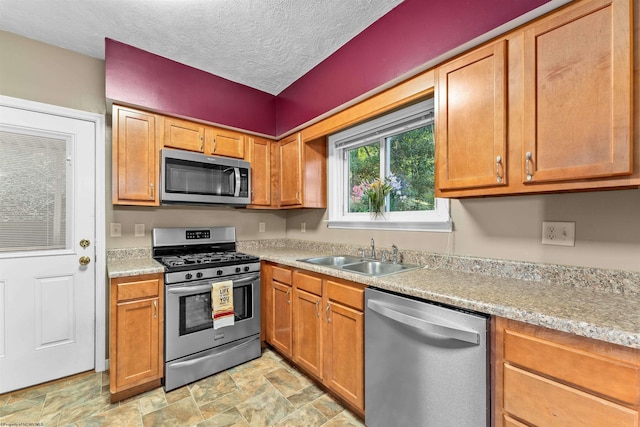 kitchen featuring a textured ceiling, appliances with stainless steel finishes, and sink