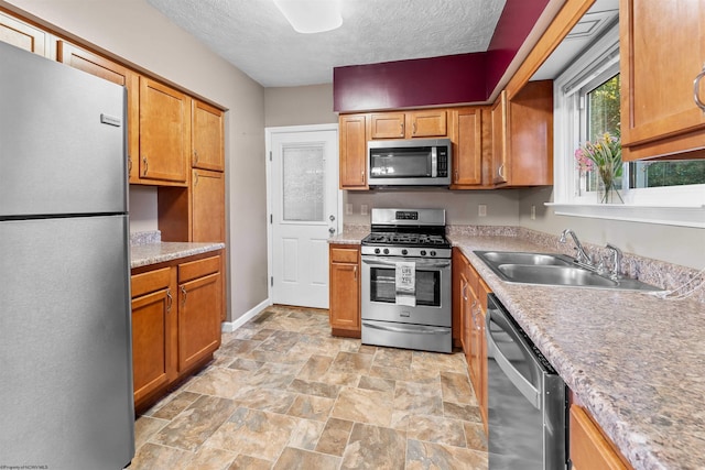 kitchen with appliances with stainless steel finishes, sink, and a textured ceiling