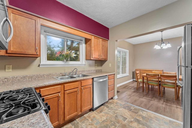 kitchen featuring light wood-type flooring, a notable chandelier, sink, hanging light fixtures, and appliances with stainless steel finishes