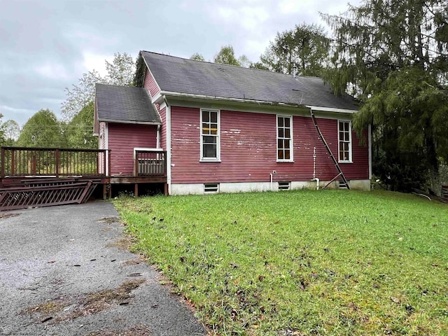 back of property with a wooden deck and a lawn